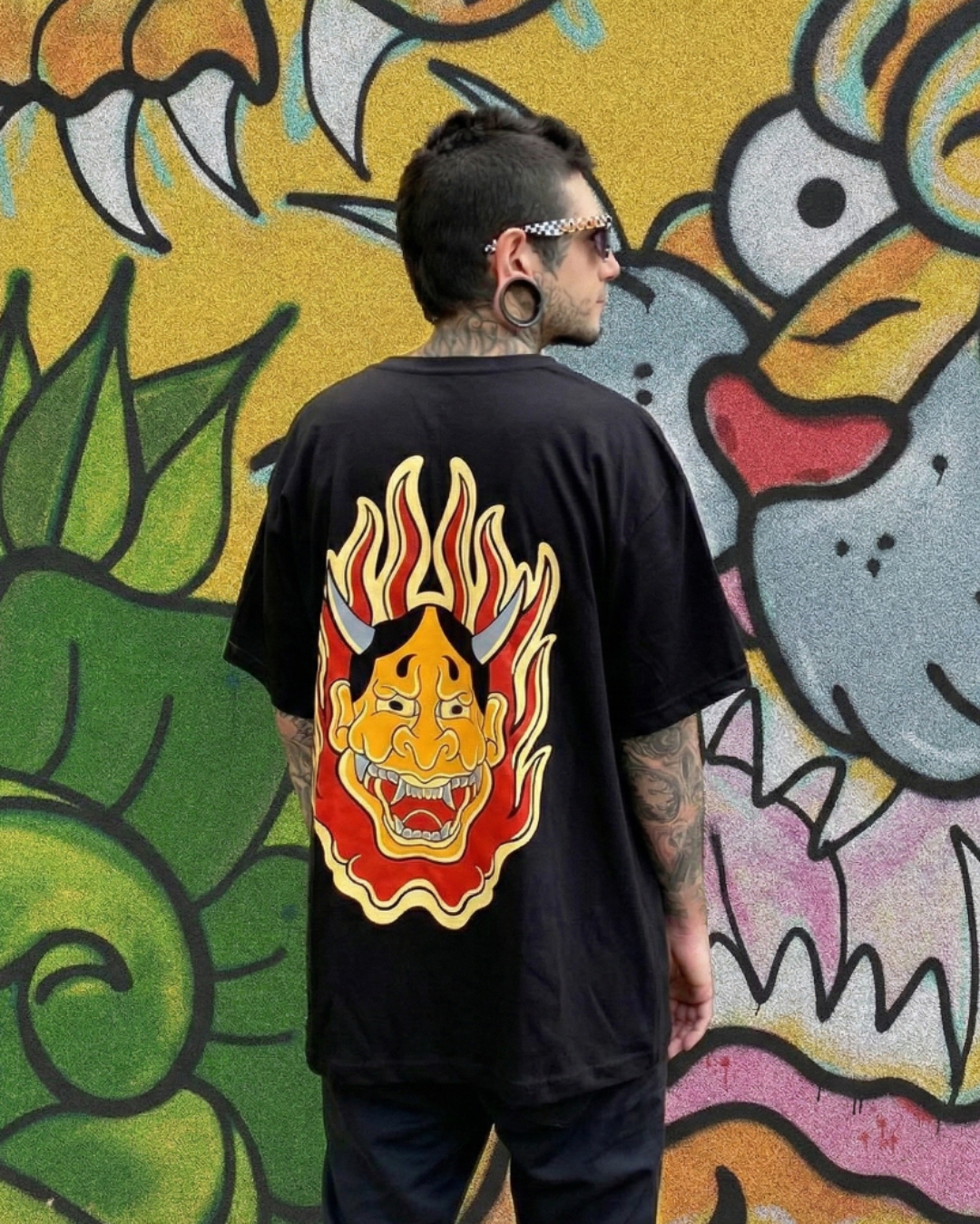 Vista posterior de camiseta Oni no Hono en modelo. Diseño de demonio Oni envuelto en llamas, arte de tatuadores colombianos.